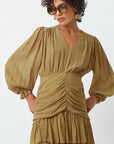 Woman wearing a beige dress with puffed sleeves on a white background