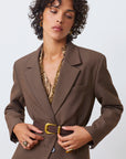 Aila choco leather belt on a model with a brown blazer with a white background