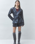 Woman wearing a metallic silver outfit with a jacket, skirt, and knee-high boots on a white background