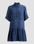 A blue crinkled cotton shirt dress with a pointed collar, short sleeves with rolled cuffs, a buttoned placket, and a tiered ruffle hem, shown against a solid light gray background.