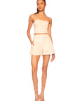 Woman wearing a beige strapless top and shorts set on a white background