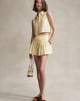 Woman wearing a yellow outfit holding a floral bag against a neutral background