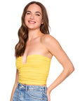 Woman wearing a yellow strapless top and blue jeans on a white background