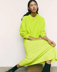 Person wearing a bright green outfit sitting against a plain background