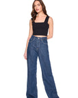 Woman wearing blue jeans and a black top on a white background, full body front