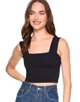 Woman wearing a black tank top and blue jeans on a white background, close up front