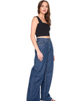 Woman wearing blue jeans and a black top on a white background, side