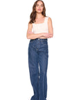 Woman wearing blue jeans and a beige top on a white background