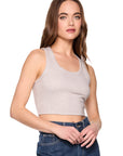 Woman wearing a beige tank top and blue jeans on a white background