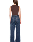 A woman shown from the back wearing a brown sleeveless top, a thin brown belt, and wide-leg blue jeans against a plain white background.