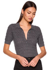 A woman wearing a dark gray short-sleeve knit polo shirt with a buttoned placket, paired with black pants, against a plain white background.
