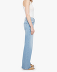 Woman wearing light blue jeans and a white top on a white background