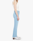 Woman wearing light blue jeans and a white top on a white background side view