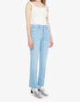 Woman wearing light blue jeans and a white top on a white background