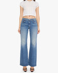 A woman modeling a white short-sleeve cropped top and blue wide-leg jeans against a plain light gray studio background.