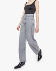 Woman wearing a black tank top and gray jeans on a white background