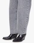 Close-up of gray jeans and black leather boots on a white background