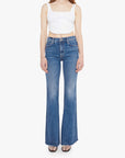 Woman wearing blue flared jeans and a white top on a white background, front