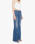 Woman wearing a white top and blue jeans on a white background. side/front view