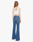 Woman wearing blue flared jeans and a white top on a white background, back