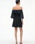 Black off-shoulder dress with ruffled details on a white background, back