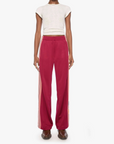 A model stands against a plain white studio background wearing a cream short-sleeve knit crop top and RED wide-leg pants with orange side stripes.