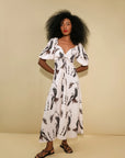 The Sol dress on a model on a beige background front view