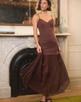 model wearing a brown dress with a fireplace and artwork in the background