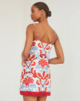 Woman wearing a floral dress with red, blue, and ivory pattern on a white background, back view