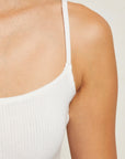 White ribbed tank top worn by a person on a plain background