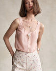 Woman wearing a pink sleeveless top and floral shorts against a neutral background