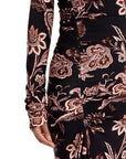 Close-up of a long-sleeve ruched dress with a black base and an intricate paisley and floral pattern in dusty pink, brown, and white, featuring a gathered side detail.