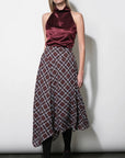 A woman modeling a sleeveless halter-neck top and matching plaid skirt set. The top is made of deep burgundy satin, while the skirt features a brown, white, and gray plaid pattern.