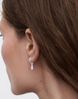 Close-up of a person wearing a diamond earring with a blurred background