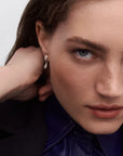 Close-up of a woman wearing earrings with a neutral background