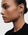 Close-up of a woman wearing a gold hoop earring against a neutral background