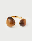 Gold ring with two large brown stones on a light gray background