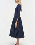 Woman wearing a navy blue dress on a white background side