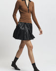 Person wearing a brown sweater and black skirt on a white background
