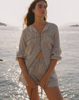 Woman in a checkered outfit standing by a body of water.