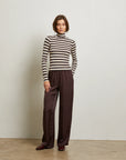 Person wearing a striped sweater and brown pants against a plain background front view