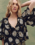 Woman wearing a black floral blouse against a green background