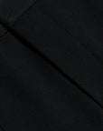 Close-up of a black fabric surface with a diagonal seam and fine woven texture.