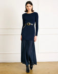 Woman wearing a navy blue dress with a belt in a minimalistic setting
