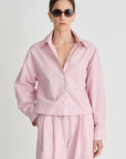 Person wearing a pink outfit with sunglasses on a light gray background