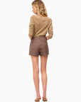 Woman wearing a beige sweater and brown shorts on a white background, full body back view