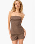 Woman wearing a brown strapless top and shorts set on a white background