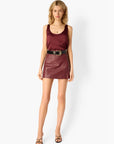 Woman wearing a burgundy sleeveless top and leather skirt on a white background