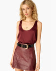 Woman wearing a burgundy sleeveless top and leather skirt on a white background, close up