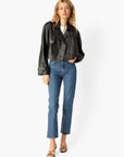Woman wearing a black leather jacket and blue jeans on a white background, front view
